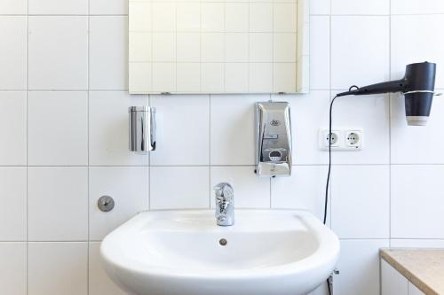 a white sink in a white tiled bathroom at Schwanthaler Hof in Munich