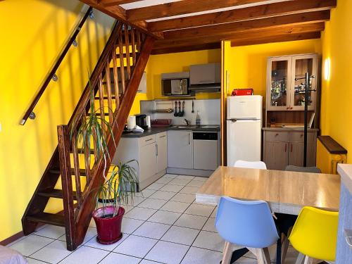 une cuisine avec des murs jaunes et un escalier en bois dans l'établissement Villa Le Mauret, à Andernos-les-Bains