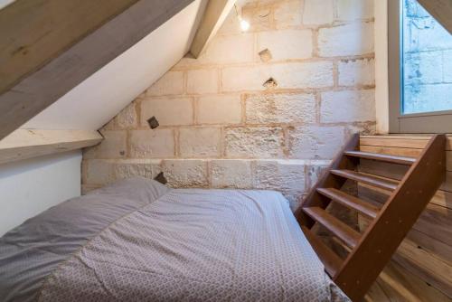 un lit dans une chambre avec un mur de briques dans l'établissement Saint Loup - Séjour à Auxerre, à Auxerre