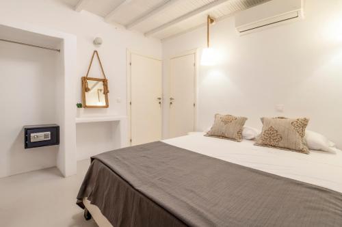 a white bedroom with a bed and a tv at Villa Infinium TWO, Sunset views 10' from Mykonos town! in Agios Stefanos