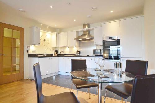 a kitchen with a glass table and chairs in a room at Travaal.©om - 2 Bed Serviced Apartment Farnborough in Farnborough