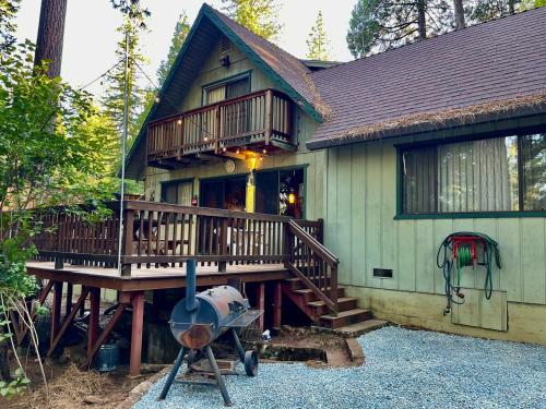 a house with a large deck and a grill at Groovy Cabin in the Woods in Pollock Pines