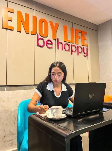 a woman sitting at a table with a laptop computer at Yours Hotel Lifestyle in Chiclayo