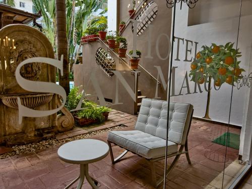 a chair and a table in a room with plants at Hotel San Marco  in Santo Domingo