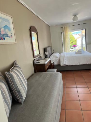 a hotel room with a couch and a bed and a mirror at Mira Mare Hotel, Galaxidi in Galaxidhion