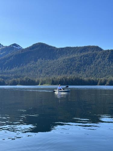 a man is sitting on a kayak on a lake at Modern Condo with Incredible Mountain Backdrop 207 in Juneau