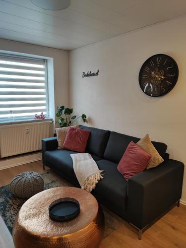 sala de estar con sofá negro y reloj en Ferienappartement Bodekessel, en Thale