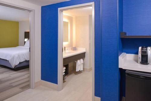 a bathroom with a blue wall with a sink and a bed at Holiday Inn Express & Suites - Shreveport - Downtown by IHG in Shreveport