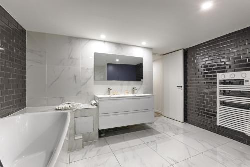 La salle de bains est pourvue d'une baignoire, d'un lavabo et d'une télévision. dans l'établissement MyKeypers - Amazing Luxury Triplex 3BR 8P - Arc de Triomphe, à Paris