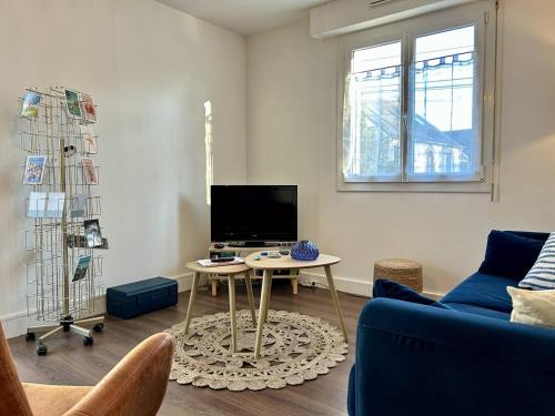 un salon avec un canapé bleu et une table dans l'établissement 1001 - Appartement T3 au cœur de Pléneuf-Val-André, à Pléneuf-Val-André
