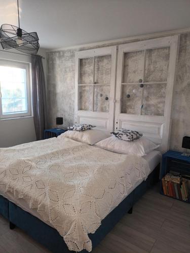 a bedroom with a large white bed with two windows at Villa Evetes in Jablonov nad Turnou