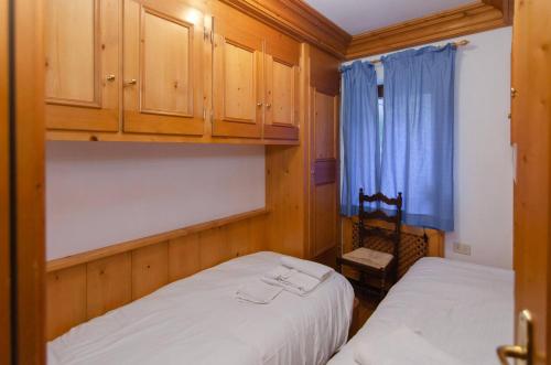 a bedroom with two beds and a blue curtain at Cà Enrosadira primo piano in San Vito di Cadore