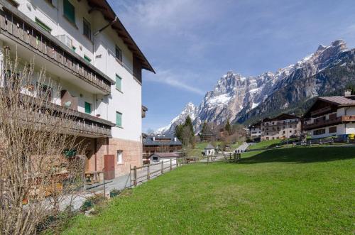 a building with a grassy field next to a mountain at Continental 101- 4 beds in San Vito di Cadore