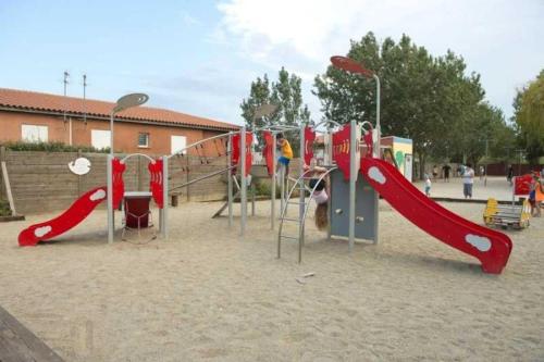 une aire de jeux avec toboggan rouge et balançoires dans l'établissement Camping 4 étoiles - Piscine - ccb0e0h, à Torreilles