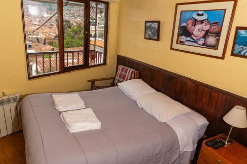 a bed in a room with a window and a bed sidx sidx sidx at Samay Wasi Hostel in Cusco