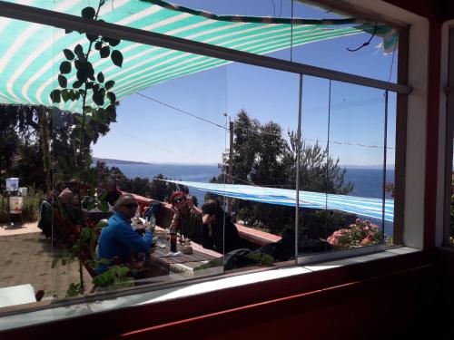 a group of people sitting at a table looking out a window at LA MANSION DEL SOL LODGE Taquile island in Isla Taquili