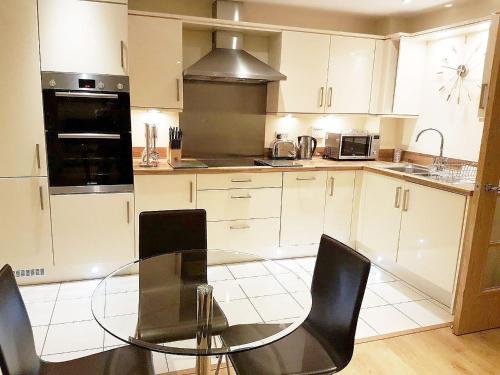 a kitchen with a glass table and black chairs at Travaal.©om - 2 Bed Serviced Apartment Farnborough in Farnborough