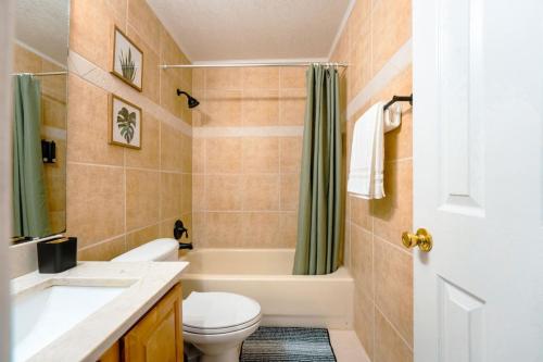 a bathroom with a toilet and a tub and a sink at Full House HotTub Mins to UCF in Bithlo