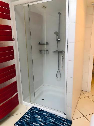 La salle de bains est pourvue d'une douche en verre et d'un tapis bleu. dans l'établissement Villa Lyne - 4 etoiles - Mimizan, à Mimizan