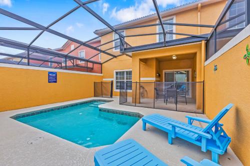 a swimming pool with two blue chairs next to a house at Wonderful 4 bed Family Home with Private Pool in Kissimmee