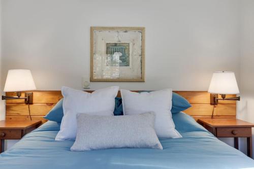a bed with blue sheets and pillows with two lamps at Family Friendly Cabin With A Firepit And A Hot Tub In Heart of Poconos in Pocono Pines