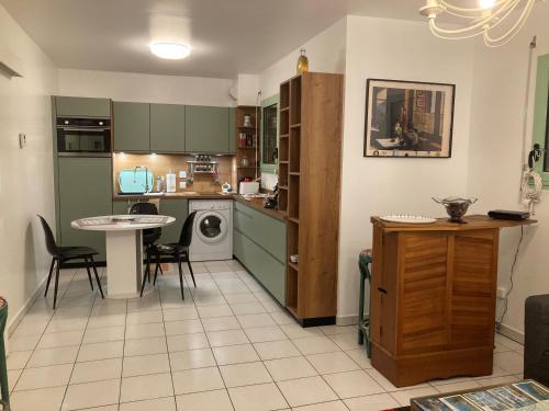 une cuisine avec des armoires vertes, une table et des chaises dans l'établissement LE CLOS Du LOC'H appartement, à Pordic