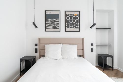 - une chambre avec un lit blanc et deux tables noires dans l'établissement Appartement Design Parisien - Palais Maillot, à Paris