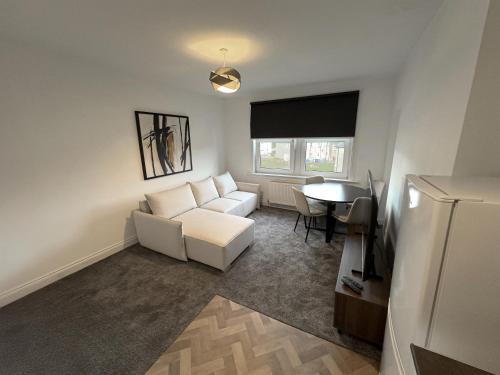 a living room with a white couch and a table at Lesmahagow Hilltop View in Lesmahagow
