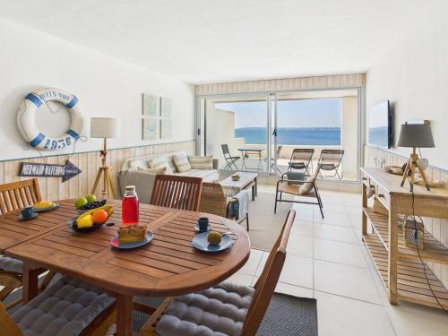 un salon avec une table et des chaises et l'océan dans l'établissement -TE MOANA- Beau T2 Bis surplombant la mer avec parking, à Concarneau