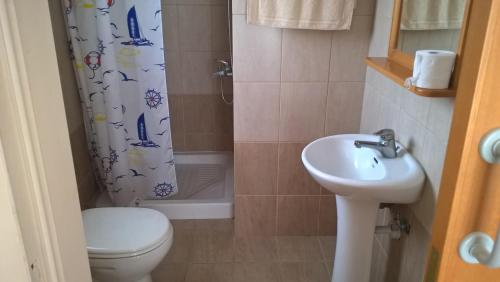 a bathroom with a toilet sink and a shower curtain at Kapsalia Holiday Villas in Pissouri