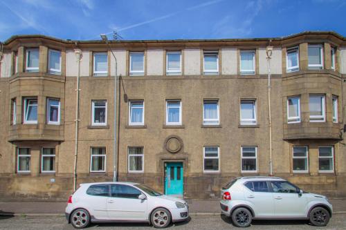 two cars parked in front of a brick building at Tobago Urban Apartment in Greenock