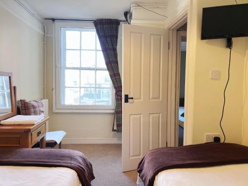 a bedroom with two beds and a window and a television at The Crown Hotel in Corwen