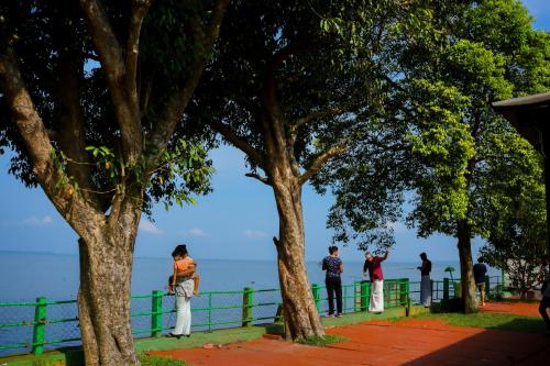 a group of people standing under trees near the water at ILLIKKALAM Lakeside Cottages Kumarakom Kerala in Kumarakom