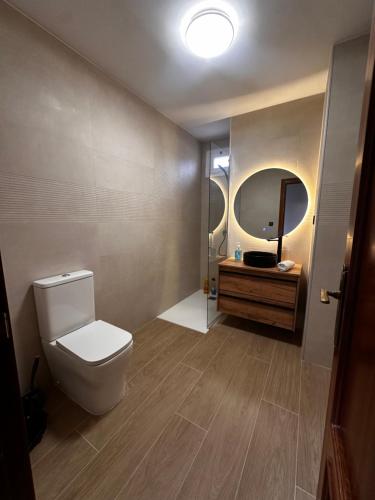 a bathroom with a toilet and a sink and a mirror at Atuaire Home Luminoso Dúplex en Reyes Católicos PARKING INCLUIDO in Burgos