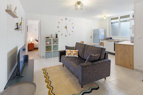 un salon avec un canapé et une horloge au mur dans l'établissement O terminus - T2 rénové - 5 min Gare et Jardin des plantes - Hyper Clame, à Nantes