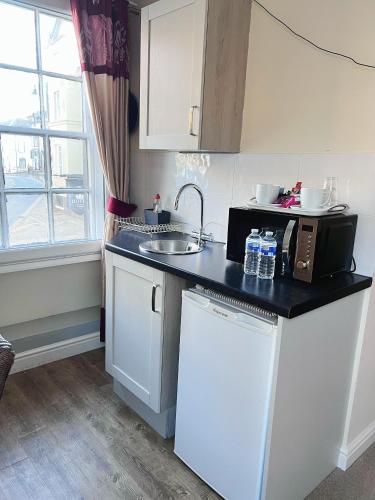 a kitchen with a sink and a microwave at The Crown Hotel in Corwen