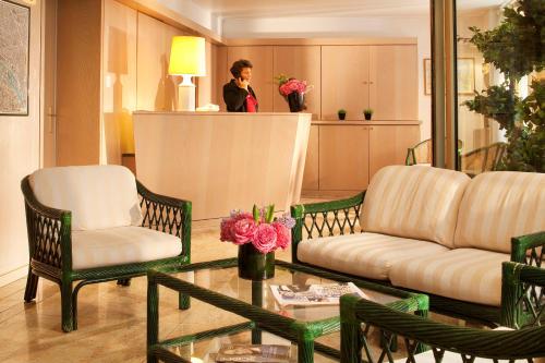 a woman standing in a living room with a couch and chairs at Au Pacific Hotel in Paris