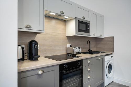 a kitchen with white cabinets and a sink and a microwave at Loch Lomond Retreat in Bonhill