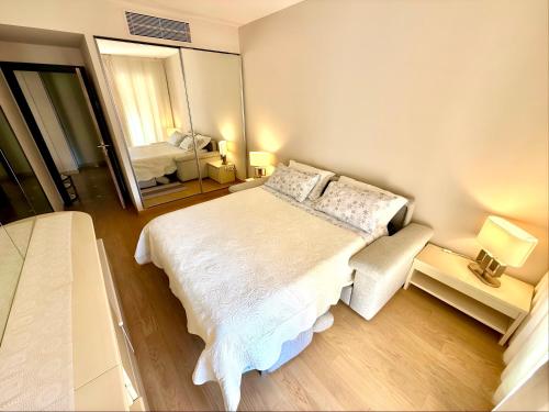 a bedroom with a large white bed and a mirror at Monaco, elegant & quiet renovated apartment, with terrace & pool, 15min walk to Port Hercule in Monte Carlo