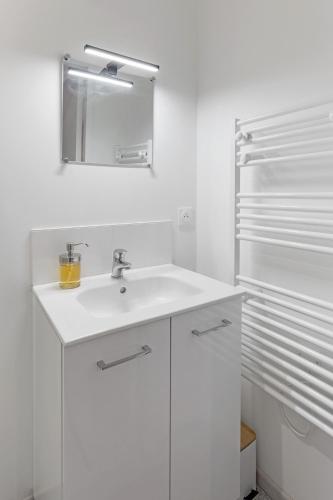 une salle de bain blanche avec un lavabo et un miroir dans l'établissement O terminus - T2 rénové - 5 min Gare et Jardin des plantes - Hyper Clame, à Nantes