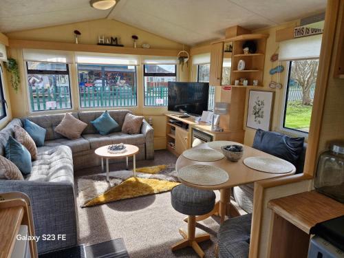 a caravan living room with a couch and a table at 3-Bed Caravan - Sleeps 8 - Pool Onsite - PetsOK in Skegness