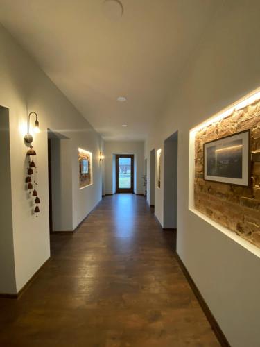 a hallway with white walls and a tile floor and a painting at Laumės dvaras in Kruopinė
