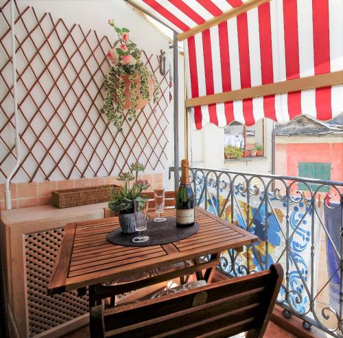 a table with a bottle of wine on a balcony at La casa del pittore con climatizzatore Pieve di Teco centro in Pieve di Teco