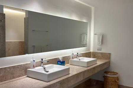 Un baño con dos lavabos y un espejo grande. en 2BR Apartment with Beach Club, en Cancún