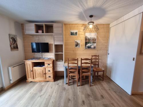 une salle à manger avec une table et des chaises et une télévision dans l'établissement appartement près des pistes le refuge des Marmottes, à Les Deux Alpes
