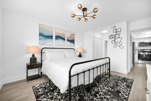 Habitación blanca con cama y lámpara de araña. en Relaxation & Luxury Pool GYM Parking WIFI, en Deerfield Beach