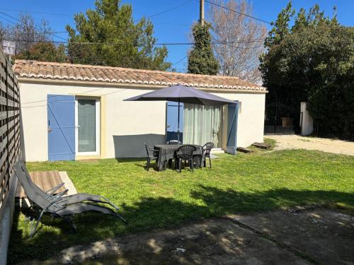 a table and chairs with an umbrella in a yard at Maison de vacances en campagne in Cavaillon