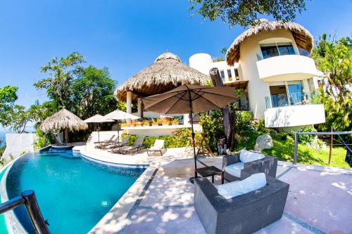 a house with a swimming pool with chairs and an umbrella at Casa Wapa Espectacular Villa Boho Chic en Acapulco in Acapulco
