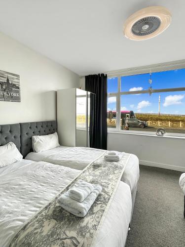 a bedroom with two beds and a window with a view at Granada Apartments Queen's Promenade in Blackpool