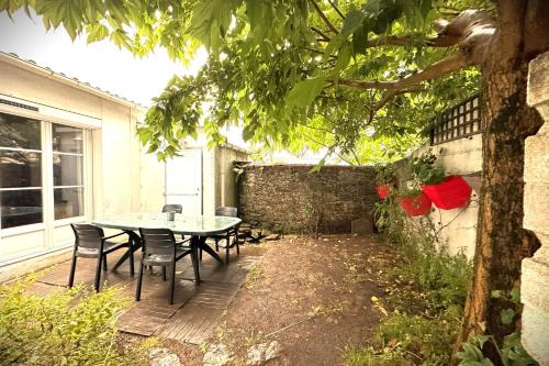un patio avec une table et des chaises dans une cour dans l'établissement L'Octroi-Maison au calme avec jardin, à Nantes